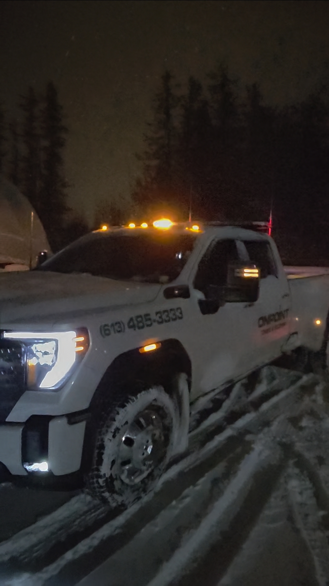OnPoint tow truck operator assisting a vehicle on a snowy Ottawa street at night